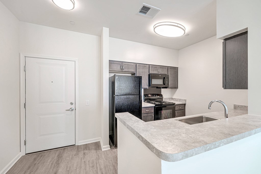 A kitchen with a white door and a black refrigerator.