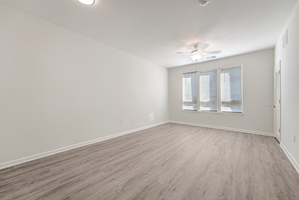 A room with a ceiling fan and a window with blinds.