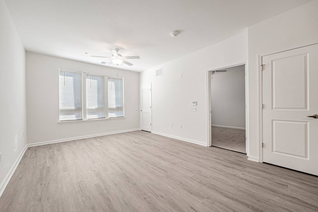 A room with a ceiling fan and a door leading to another room.