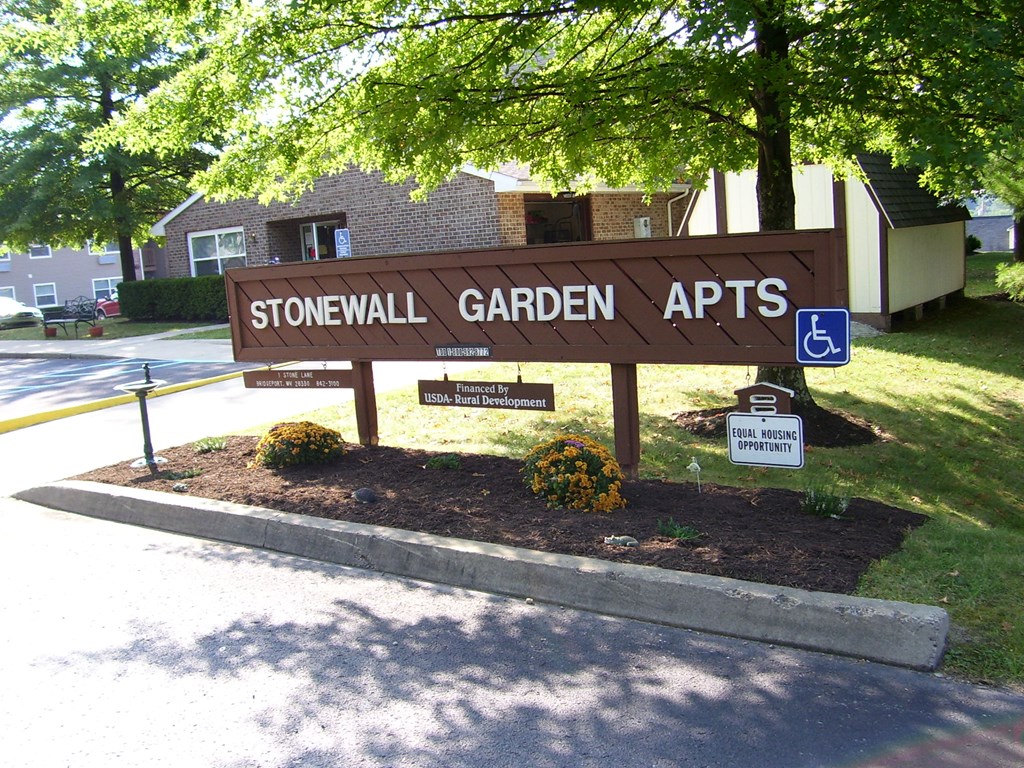 A brown sign that says Stonewall Garden Apts.