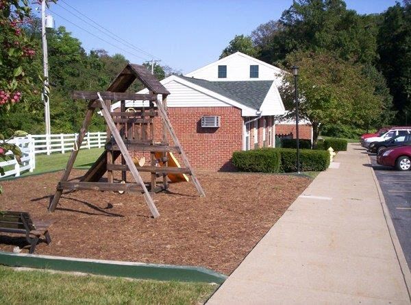 a wooden swing set in a yard in front of a house