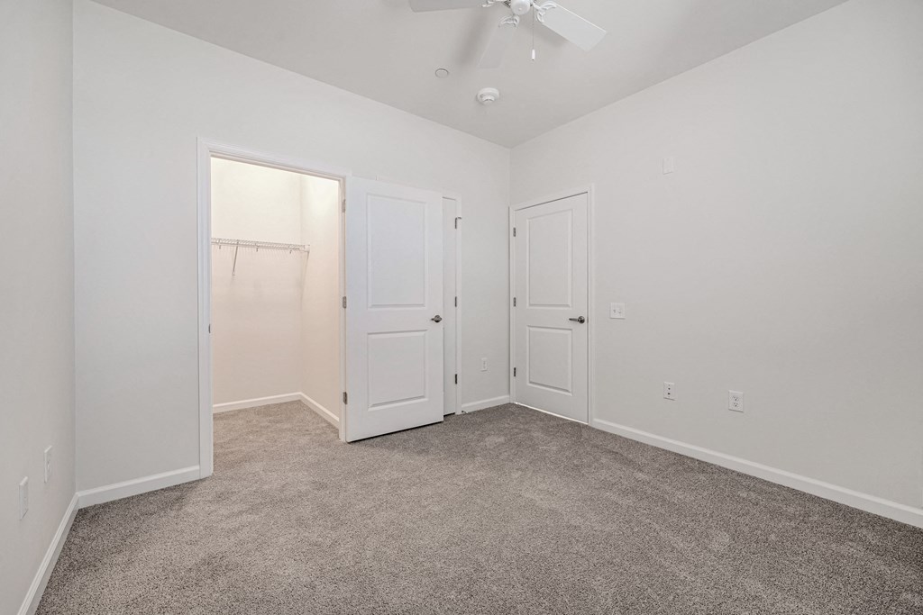 A room with a carpeted floor and a ceiling fan.