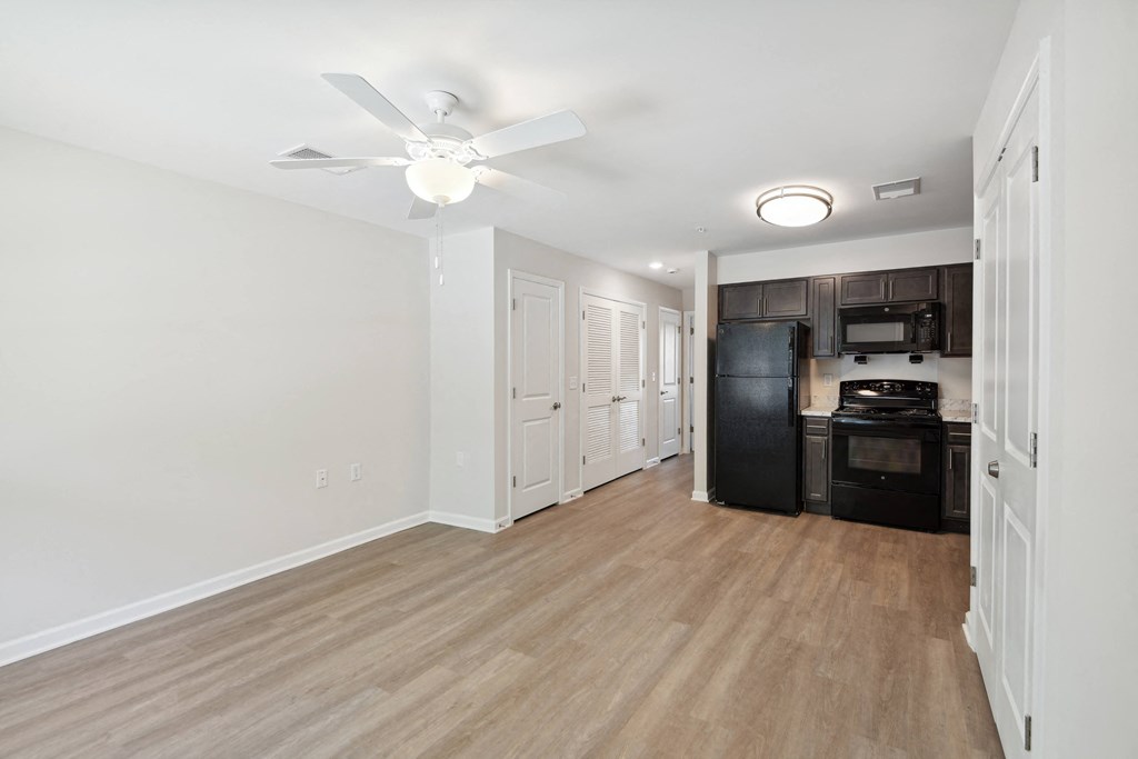 a renovated living room and kitchen with wood flooring and a ceiling fan