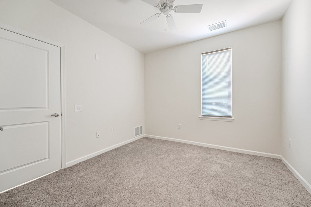 A room with a ceiling fan and a window with blinds.