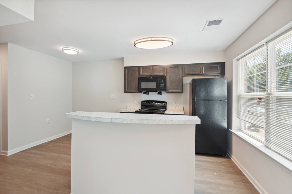 a kitchen with a white counter top and a black refrigerator