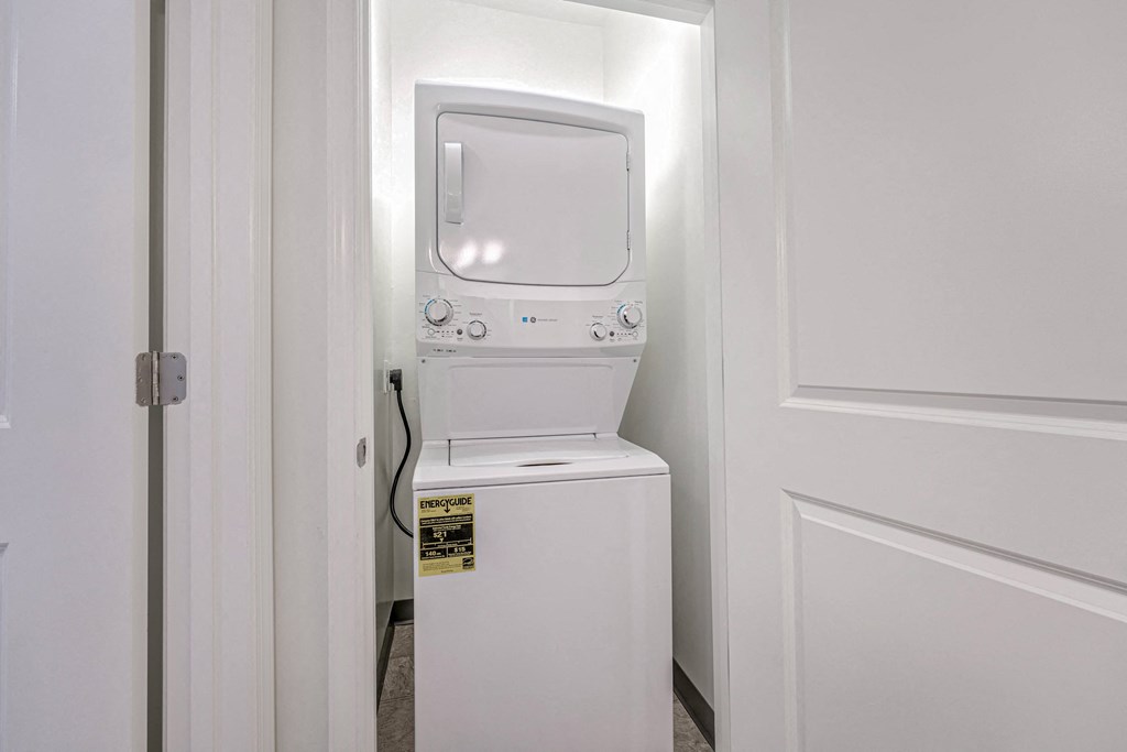 A white washing machine is in a small white room.