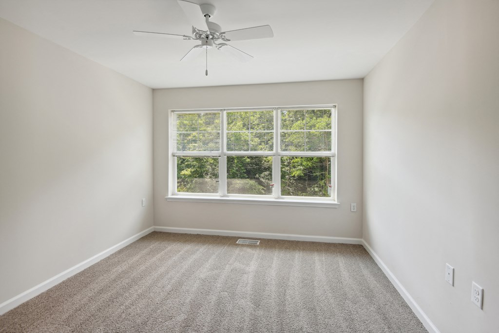 an empty room with a window and a ceiling fan