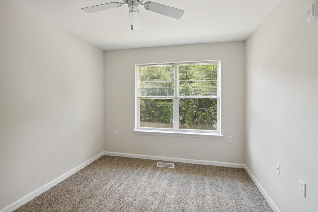 an empty room with a window and a ceiling fan