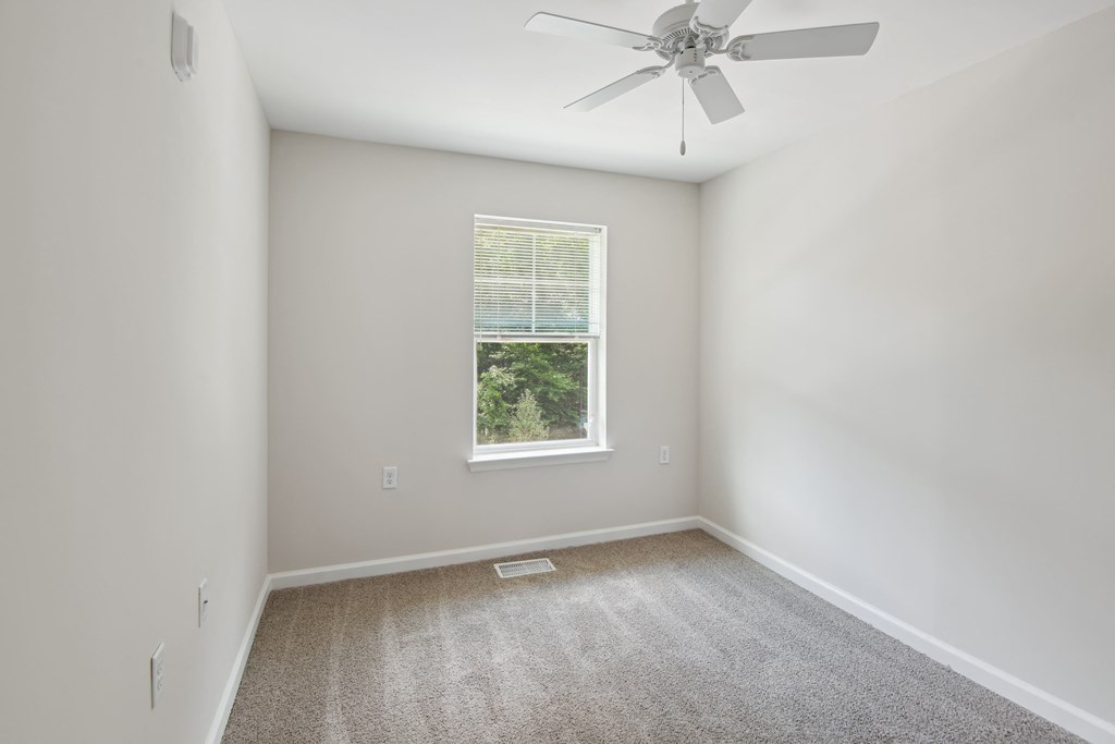 an empty room with carpet and a ceiling fan