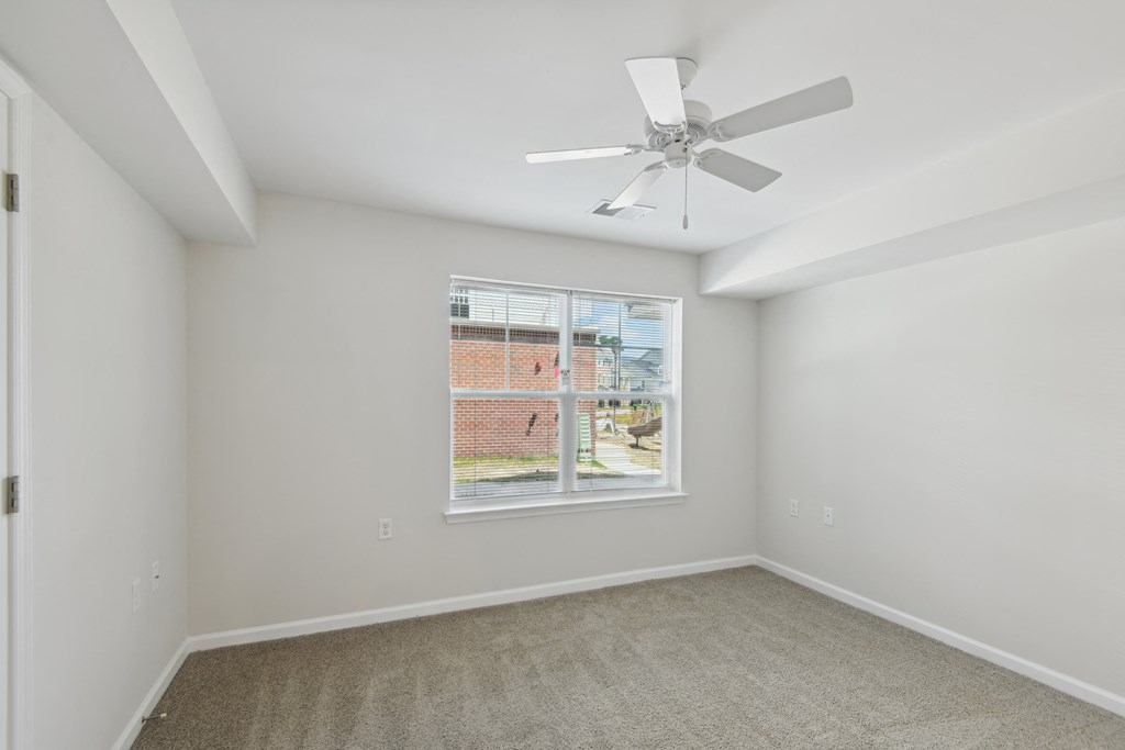 an empty room with a large window and a ceiling fan