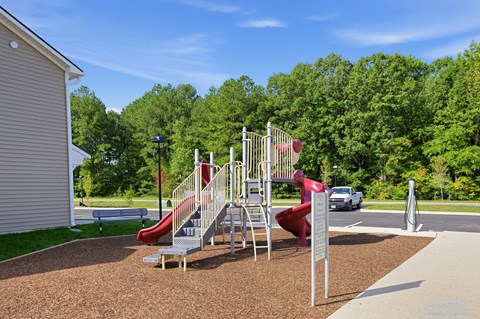 A playground with a red slide and a grey slide.