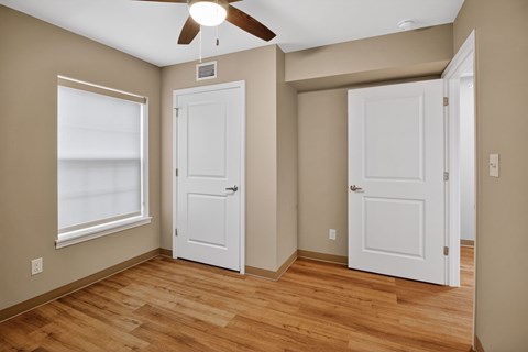 A room with a ceiling fan and two white doors.