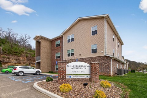 A building with a sign that says Children's Crossing Apartments.