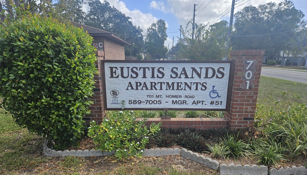 A sign for Eustis Sands Apartments is displayed in front of a building.