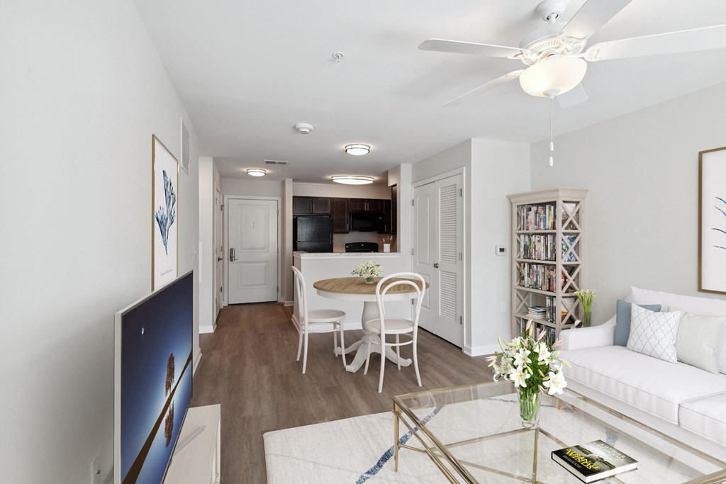 a living room and dining room with a white couch and a table and a kitchen