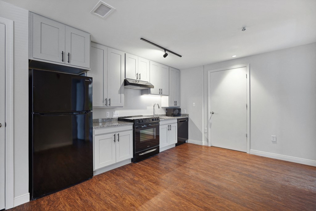 a kitchen with white cabinets and black appliances