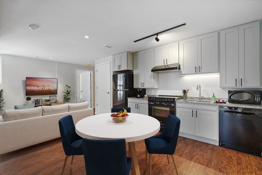 a kitchen and living room with white cabinets and a white table and chairs