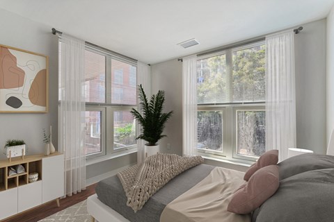 a bedroom with large windows and a bed and a potted plant