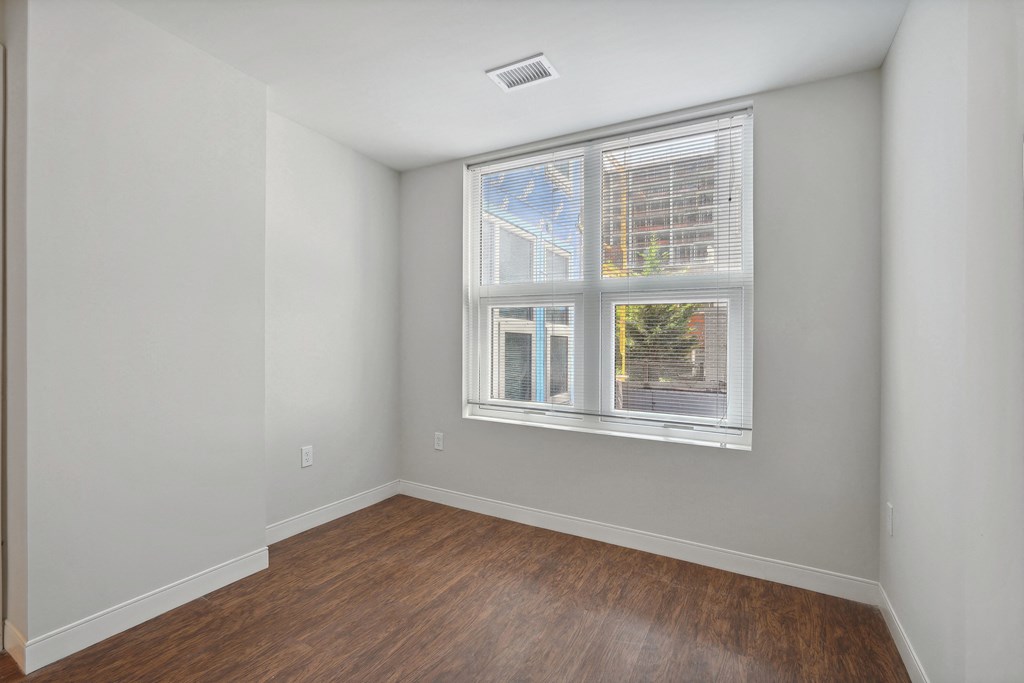 a bedroom with a large window and hardwood floors