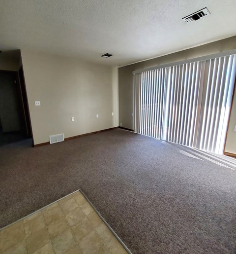 an empty living room with blinds on the window