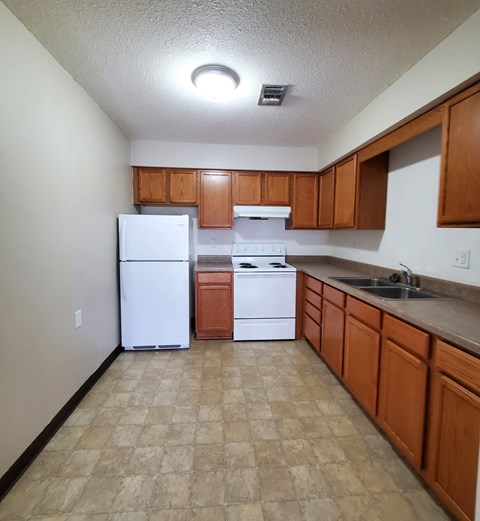 an empty kitchen with white appliances and wooden cabinets