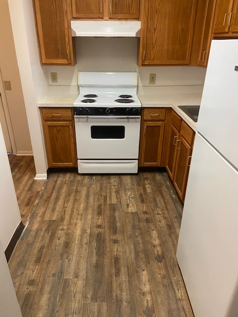 A kitchen with a white stove top oven and white refrigerator.