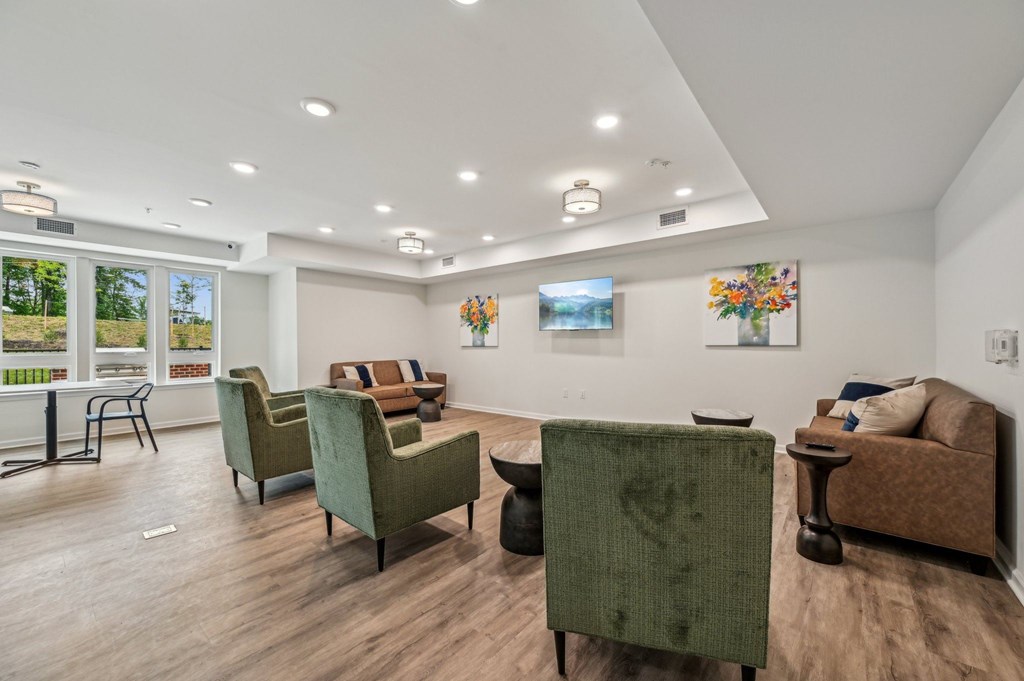 A living room with a green chair in the foreground and a painting on the wall.