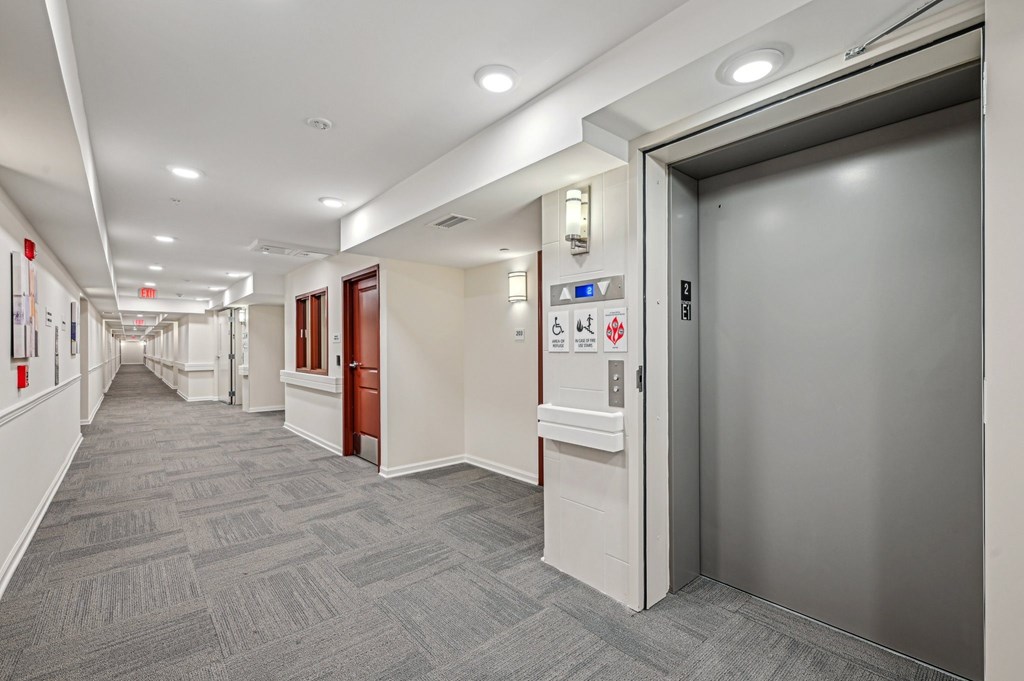 A long hallway with a silver elevator on the right.