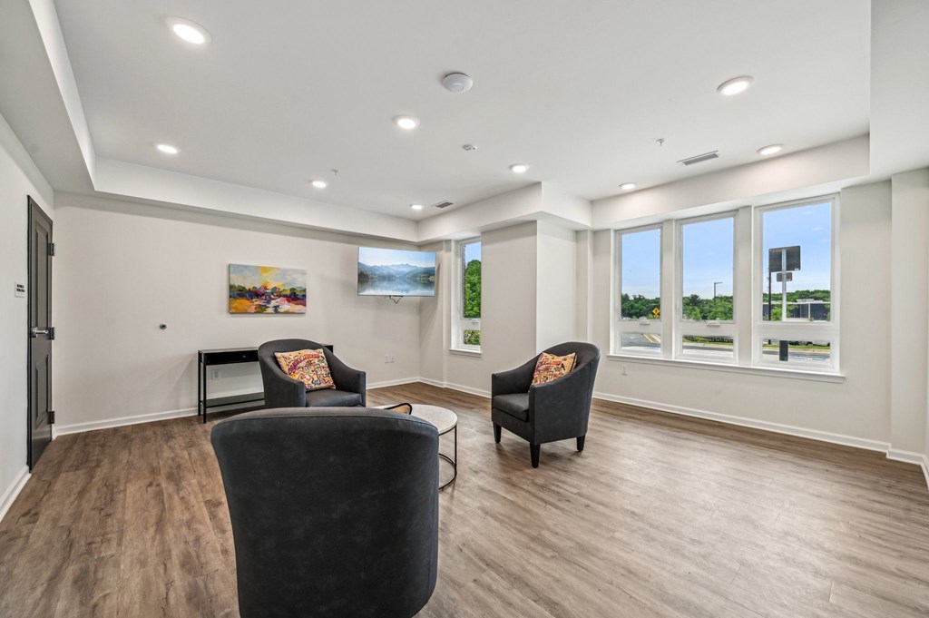 A spacious living room with two black armchairs and a coffee table.