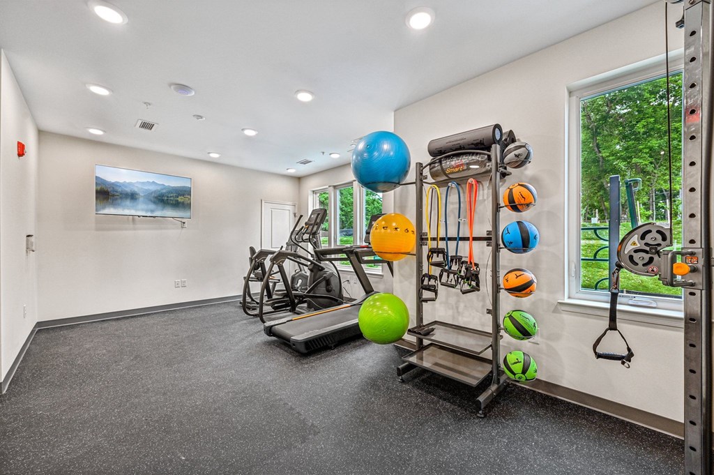 A gym room with a treadmill, exercise balls, and resistance bands.