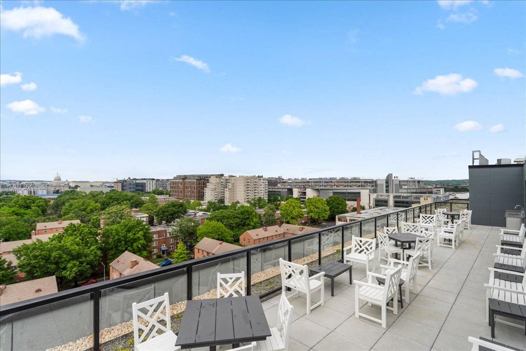 a rooftop patio with tables and chairs and a view of the city