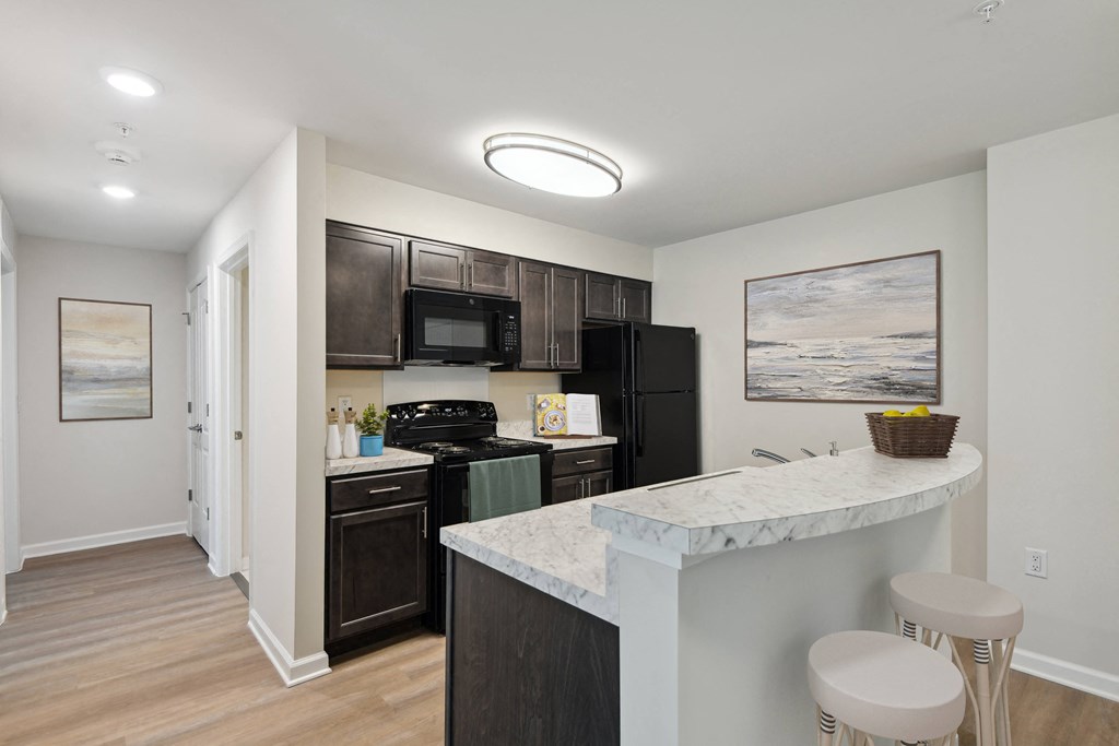 a kitchen with black appliances and a counter with two stools