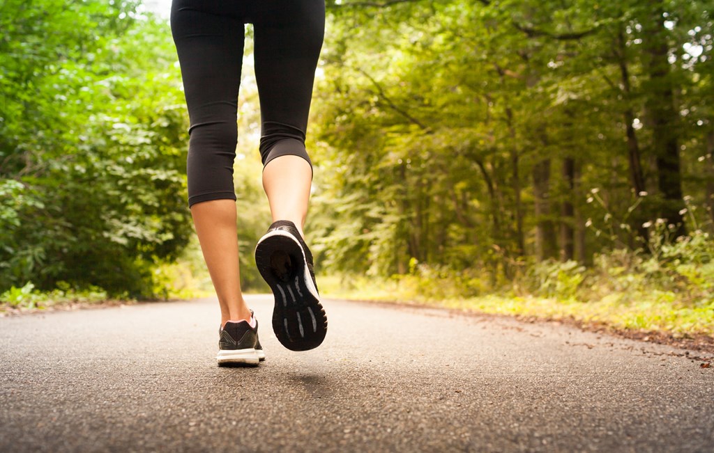 a woman walking down a road in the woods