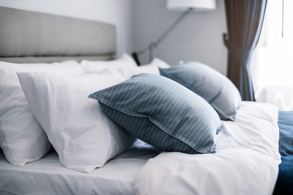 a bed with blue and white pillows and white sheets