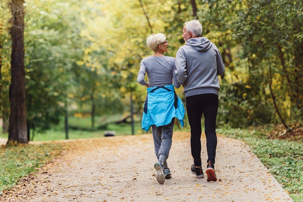 an older couple walking down a path in the park