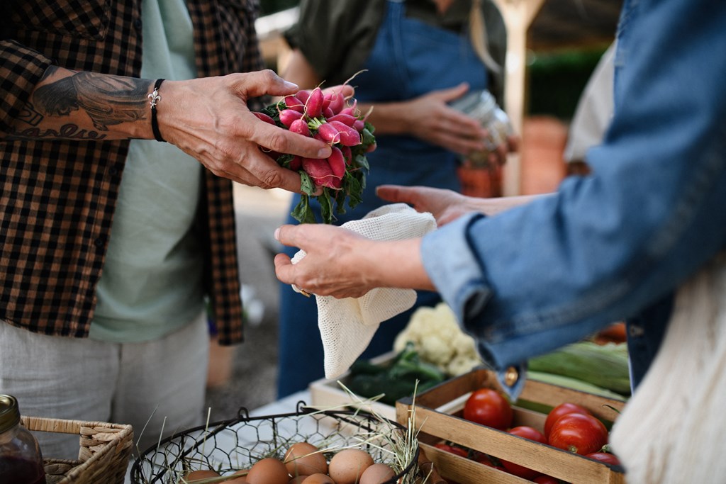 a person handing a bouquet of flowers to another person at a farmers market