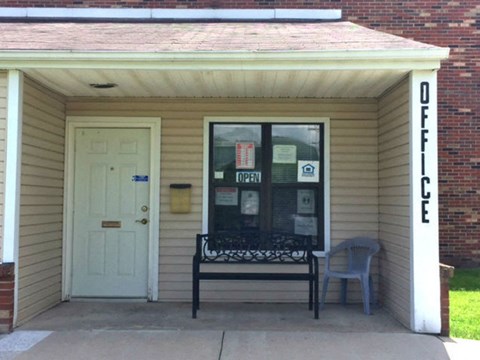 A small building with a bench in front of it.
