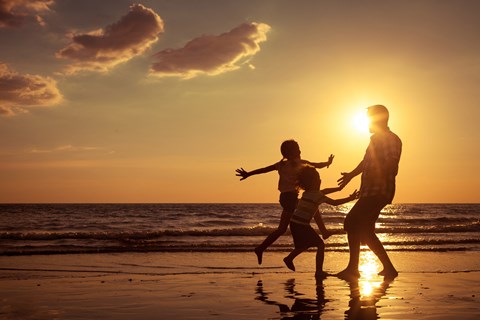 Two people are running on the beach at sunset.