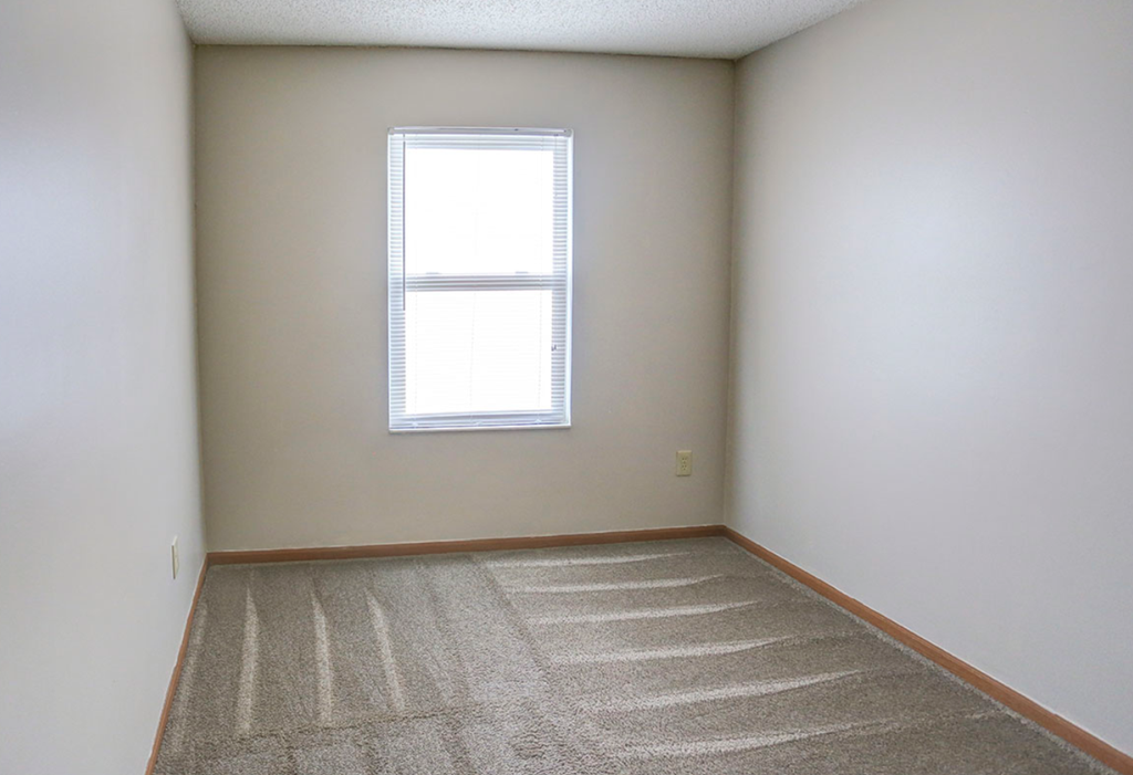 an empty room with a window and a carpet