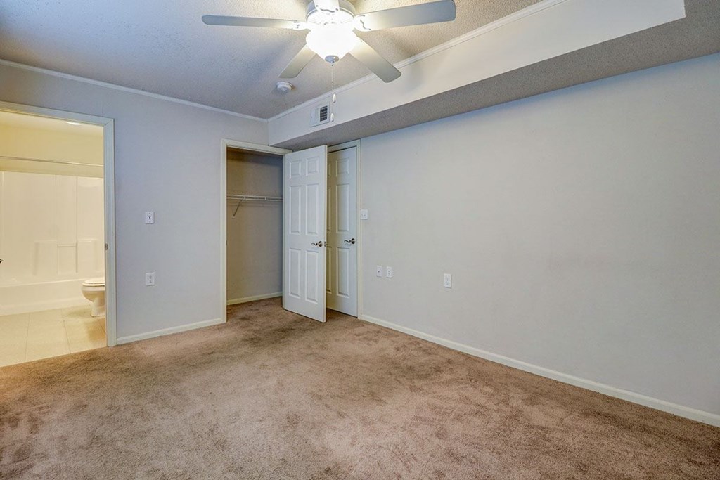 an empty living room with a ceiling fan and a closet