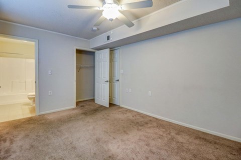 an empty living room with a ceiling fan and a closet