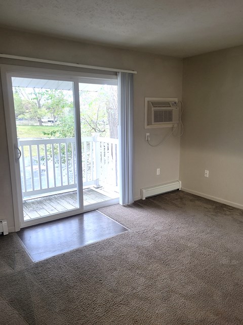 an empty living room with a door to a balcony