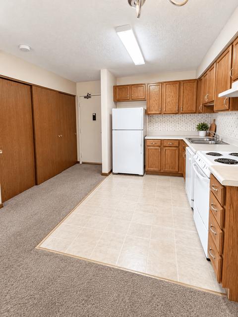 A kitchen with a white refrigerator and wooden cabinets.