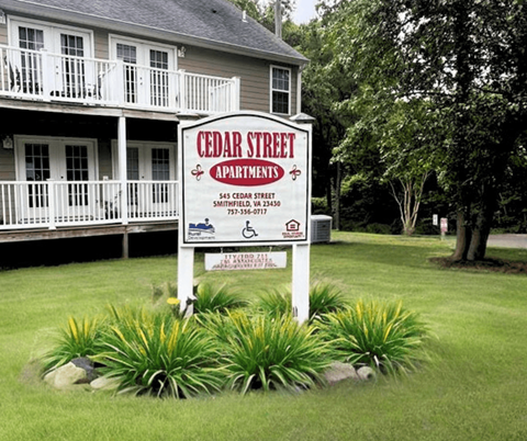 a sign in the front yard of a house with a white house
