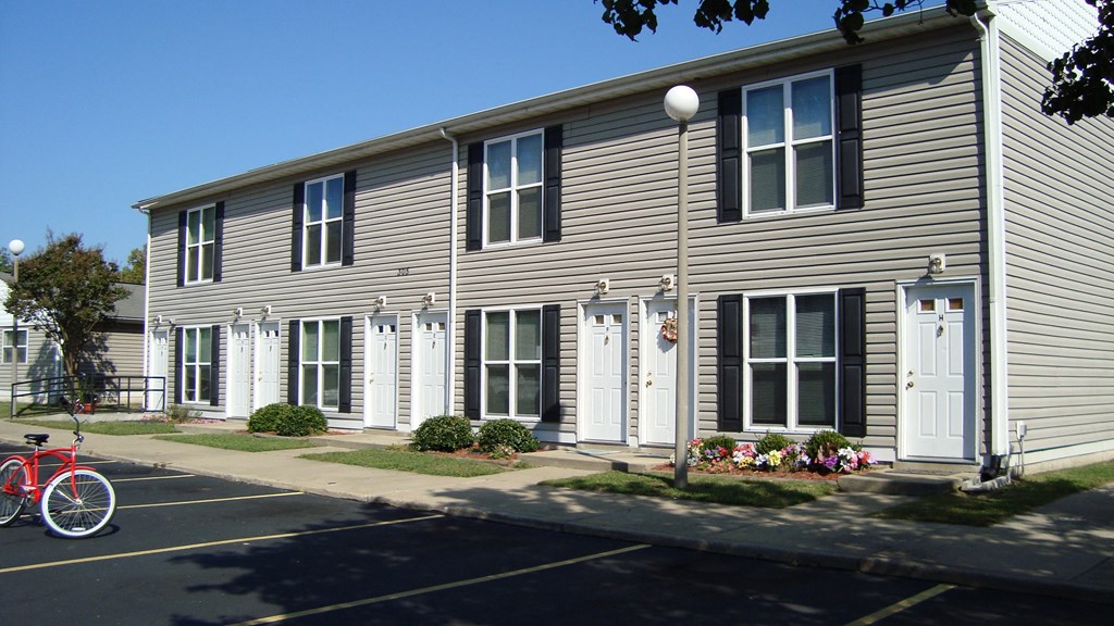 A grey building with a red bicycle parked in front.