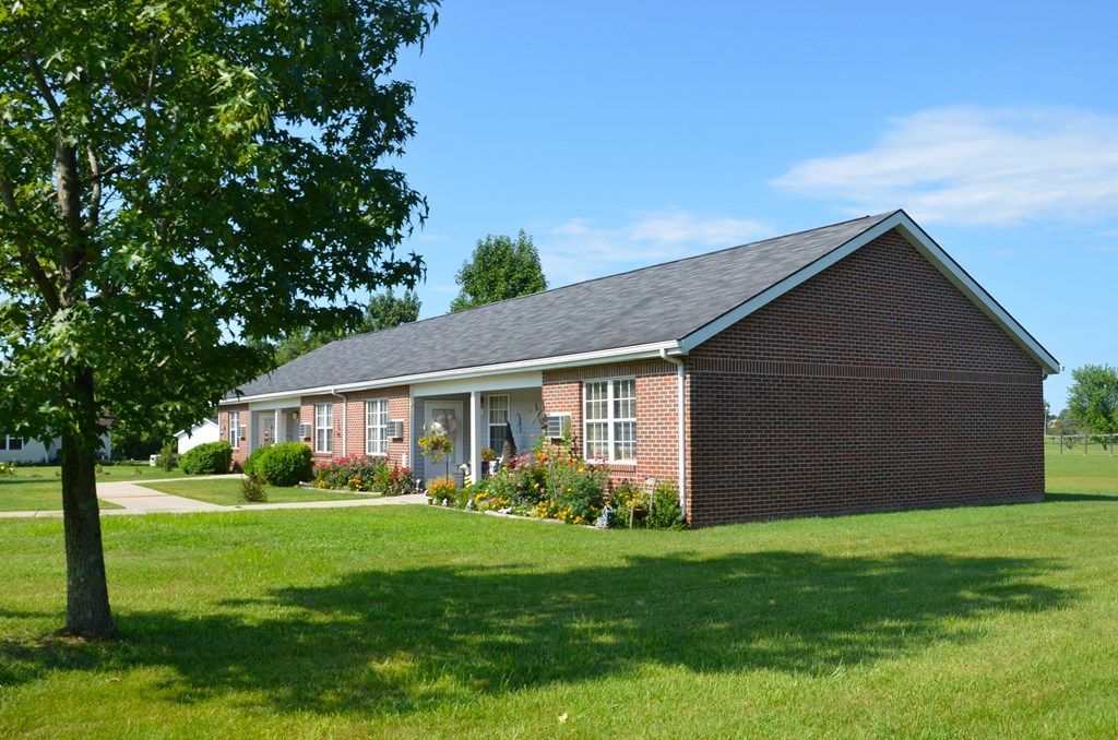 a brick house with a lawn and a tree