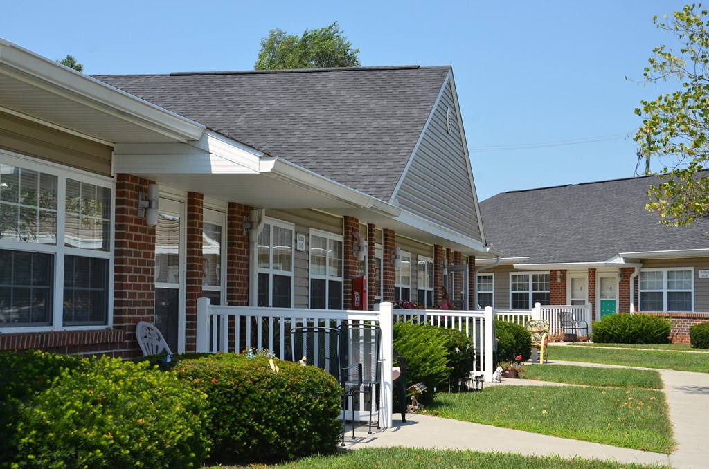 a row of houses with a porch and a white fence
