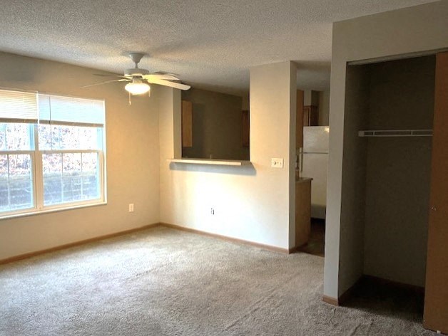 an empty living room with a ceiling fan and a window