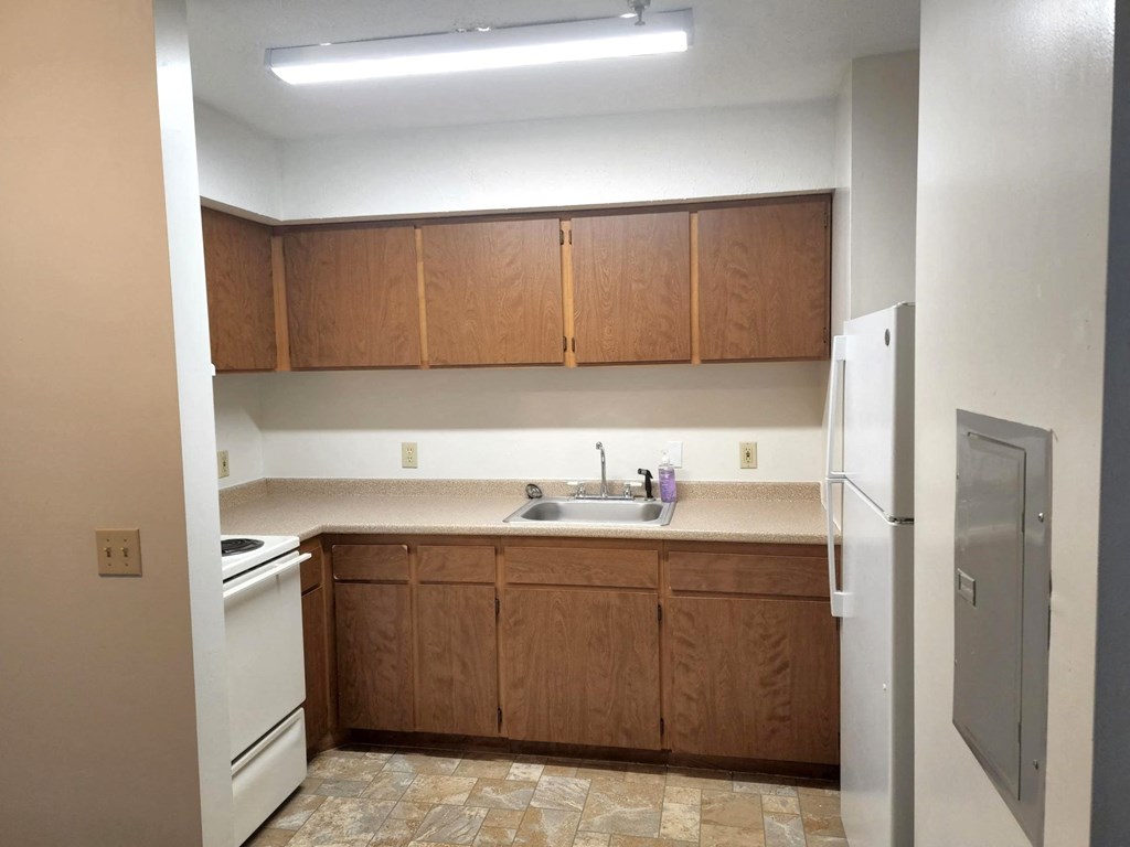 an empty kitchen with white appliances and wooden cabinets