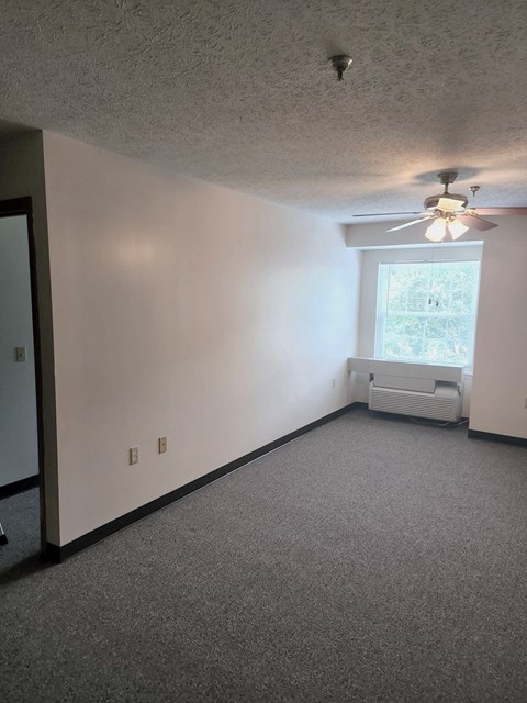 an empty room with a ceiling fan and a window